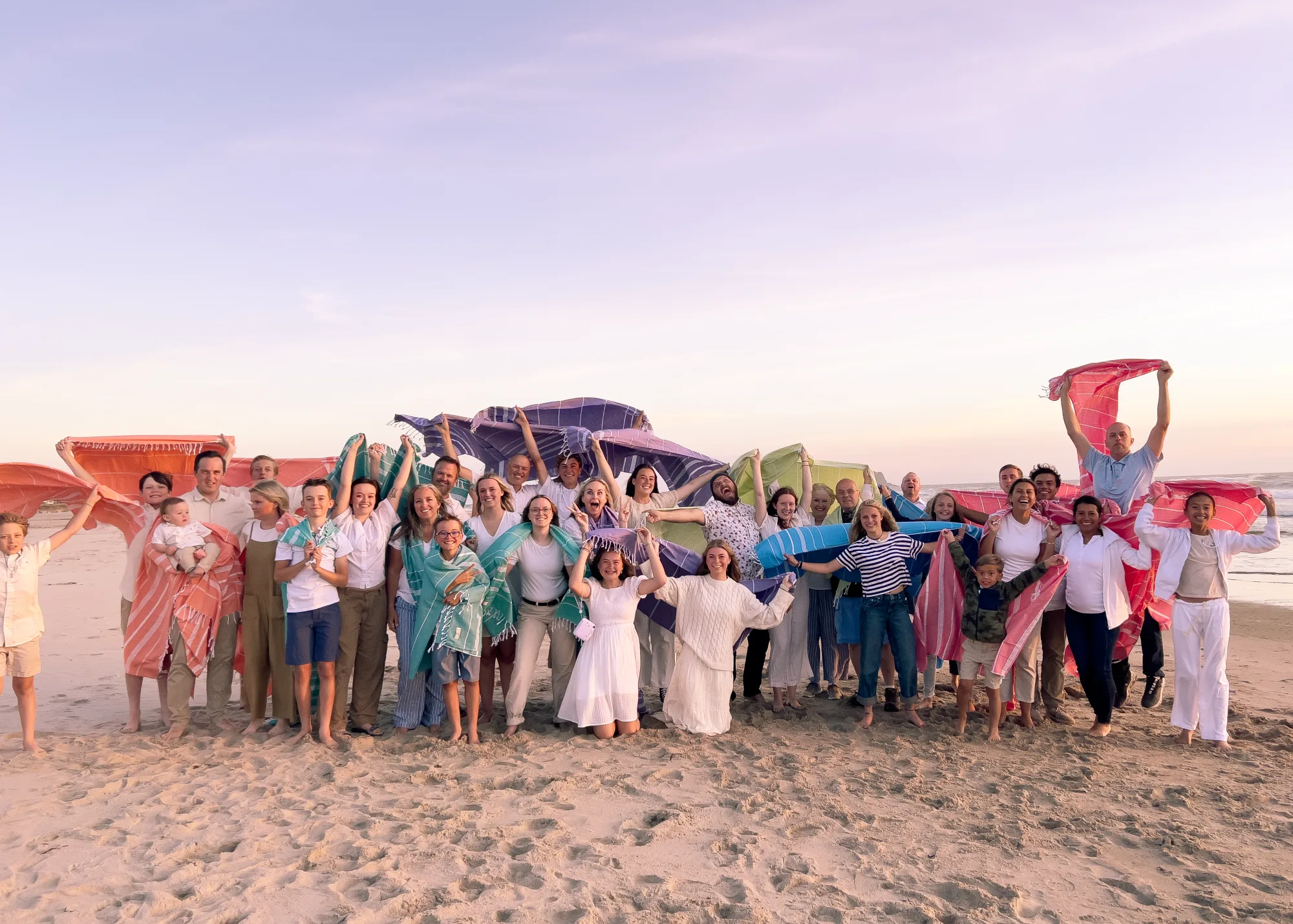 Three generations of an extended family together on the beach at sunset